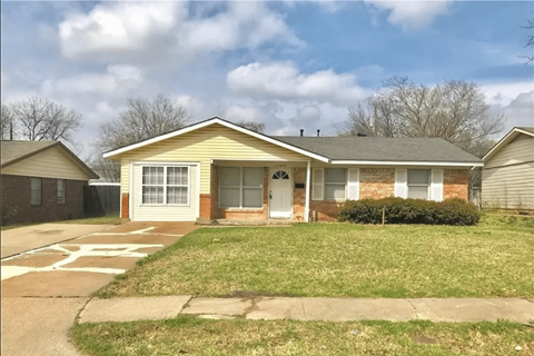 a small yellow house with a lawn and a driveway